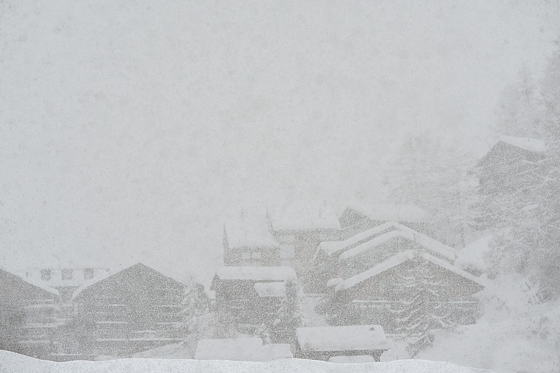 Severe scenery of remote rural village houses covered with thick layer of snow during intense snowstorm on cold winter day