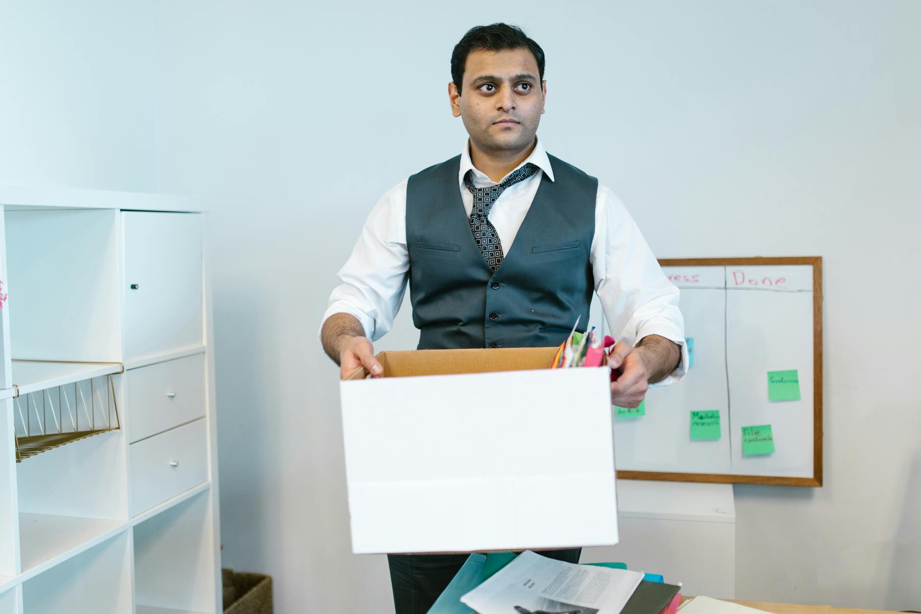 Professional man organizing office belongings in a cardboard box, preparing for transition.