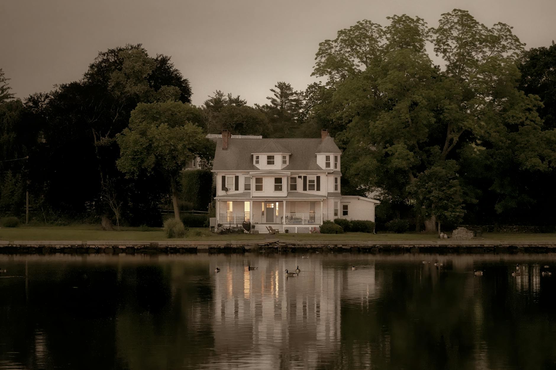 A serene view of a colonial house reflecting on water at twilight in Stamford, Connecticut.