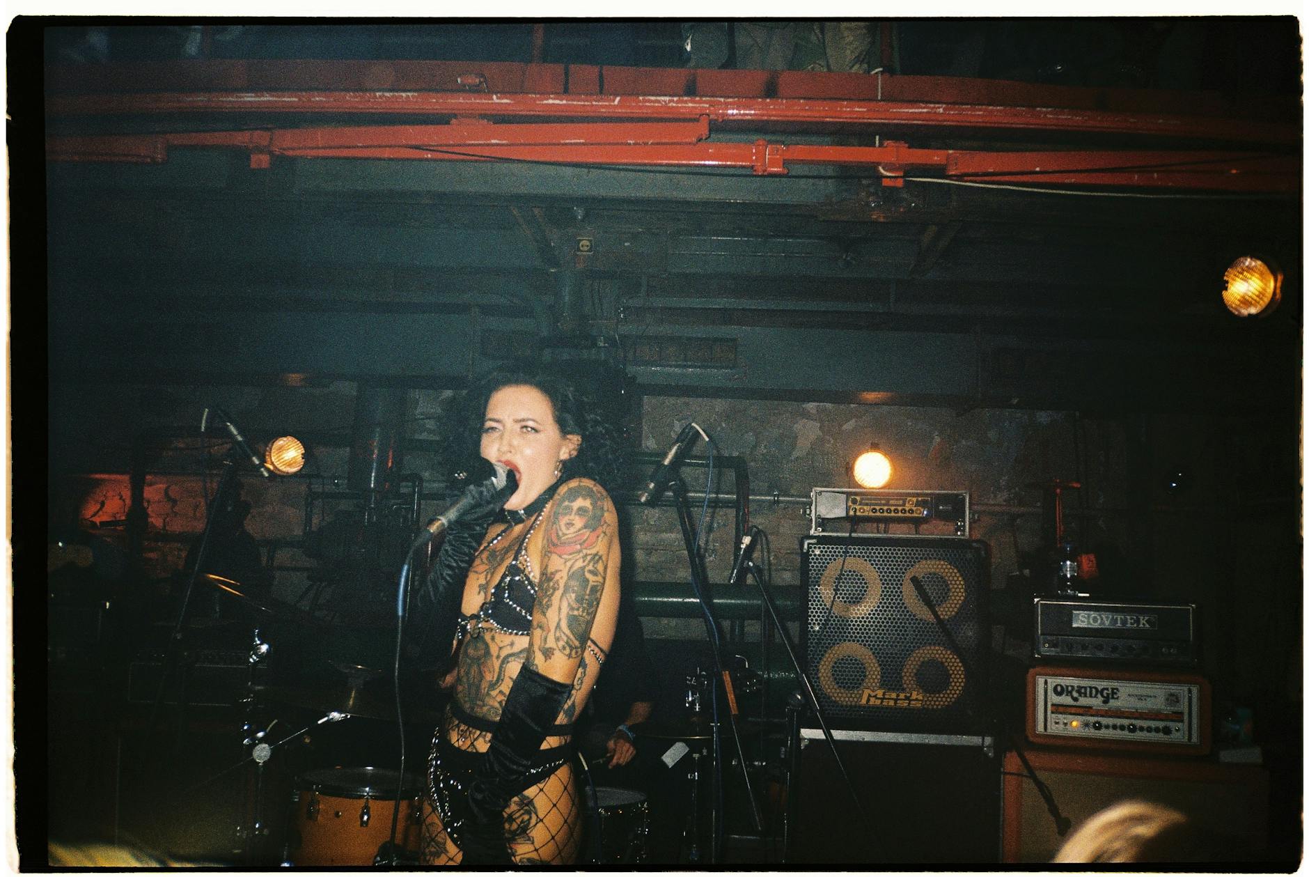 Tattooed female punk singer performing energetically on stage at a concert.